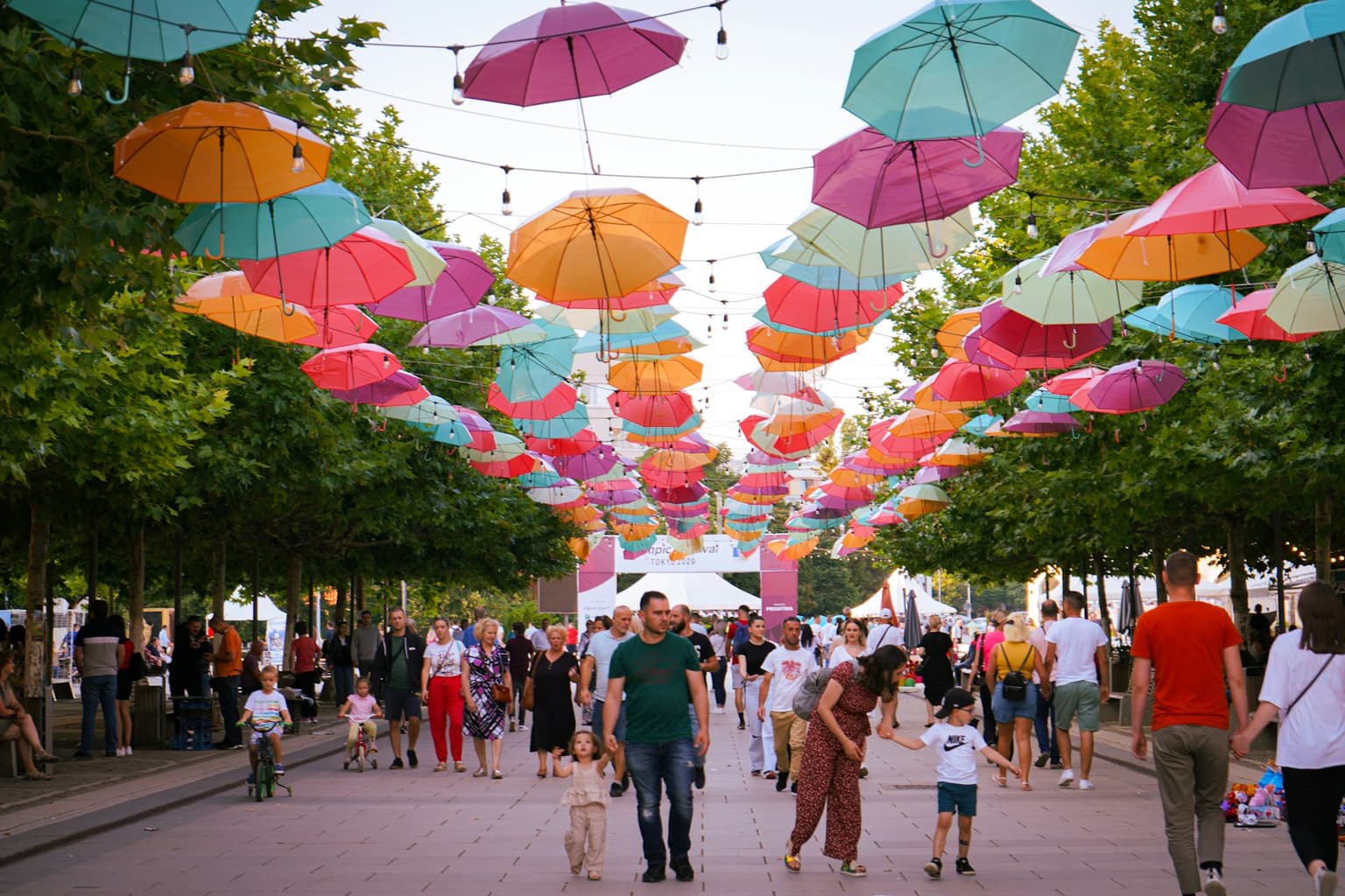 Colorful umbrellas strung above a busy pedestrian boulevard in Pristina